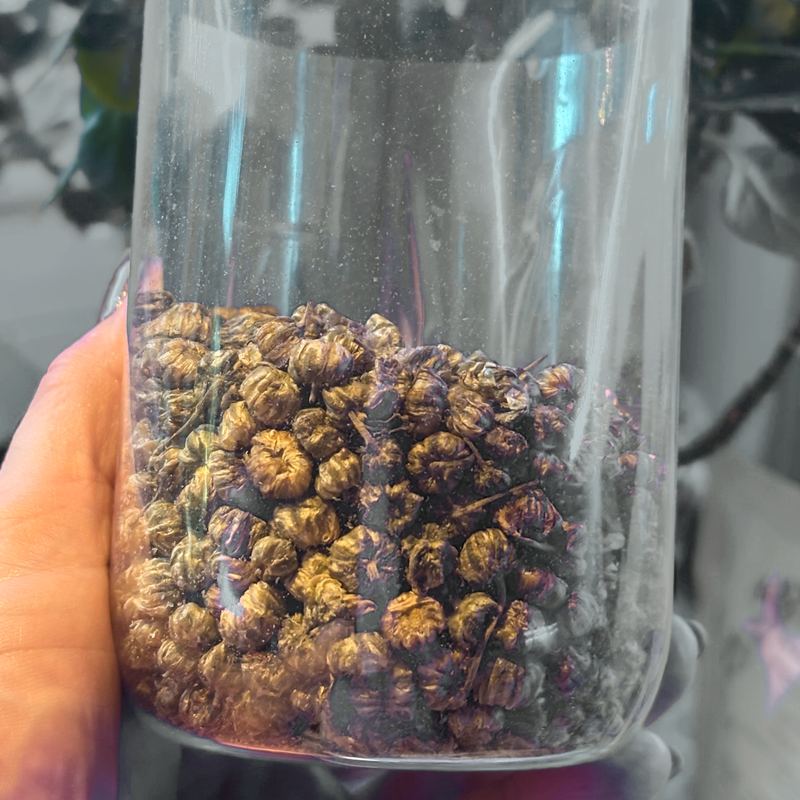 A glass jar filled with whole dried chrysanthemum buds