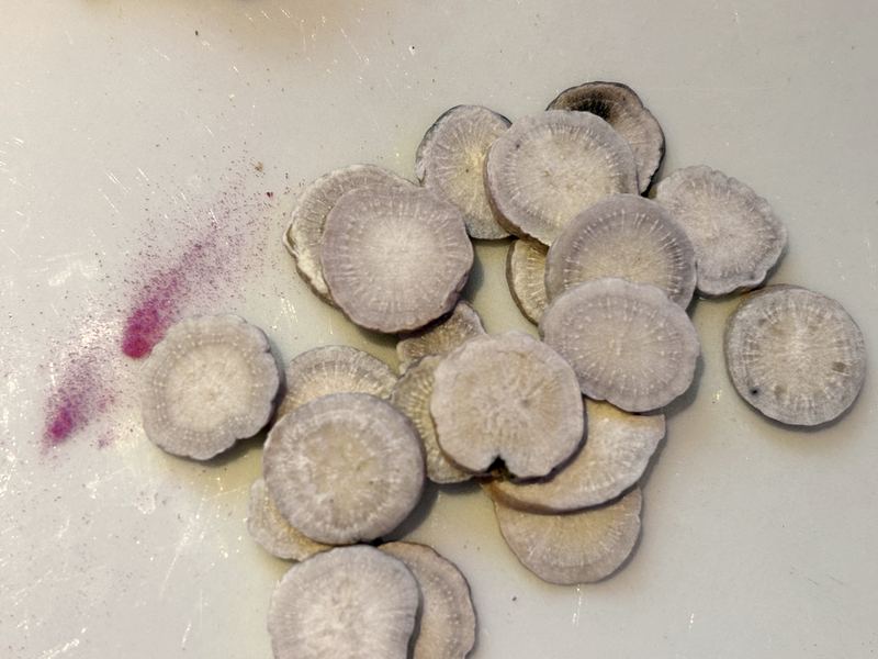 Dried white peony root slices on a white surface